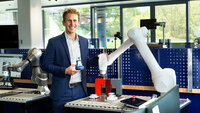 Mann mit Roboterarm in moderner Arbeitsumgebung