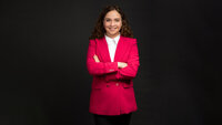 Professionelle Frau in einem pinken Blazer mit verschränkten Armen