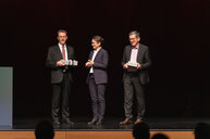 Preisverleihung mit drei Personen auf der B&uuml;hne