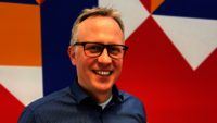 Lächelnder Mann vor buntem Hintergrund