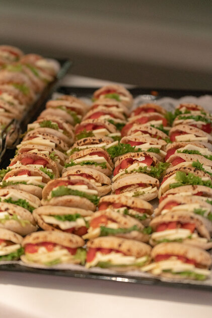 Eine große Platte mit frisch zubereiteten Sandwiches, gefüllt mit Salat, Tomaten und Käse, perfekt für ein Buffet.