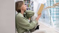 Frau sitzt auf dem Boden und liest ein Buch