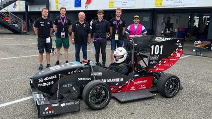 Teamfoto mit Rennwagen und Ingenieuren bei einem Motorsport-Event