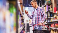 Mann beim Einkaufen im Supermarkt mit Einkaufswagen