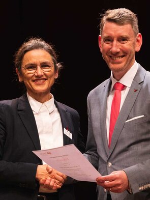 Zwei Personen bei einer feierlichen &Uuml;bergabe eines Zertifikats