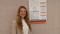 Frau mit langen Locken vor einem wissenschaftlichen Poster