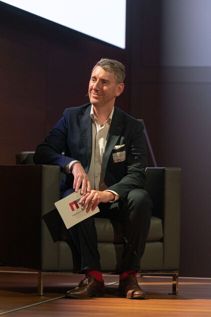 Ein lächelnder Mann auf einer Konferenzbühne