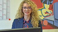 Professionelle Frau mit lockigem Haar am Schreibtisch