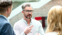 Mann mit Brille erklärt ein Konzept in einer Gruppe