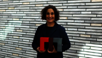 Frau mit bunten Büchern vor einer modernen Wand