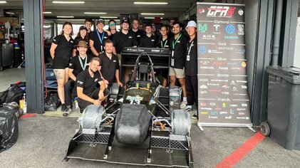 Teamfoto mit Rennwagen und begeisterten Mitgliedern